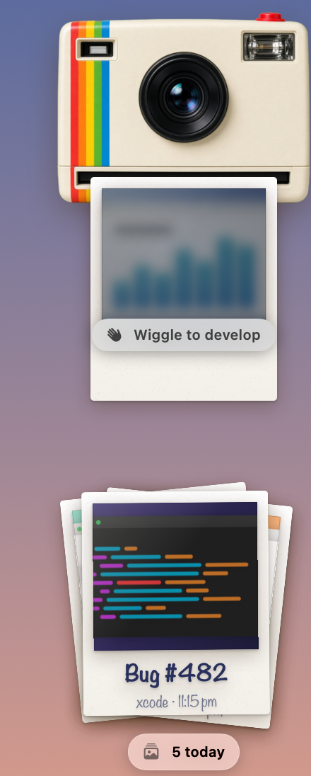 The cream instant camera with a rainbow stripe in the corner of the screen, a new print feeding out of its slot with a “Wiggle to develop” hint, above a small pile of earlier prints.